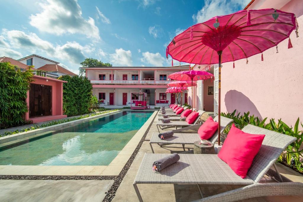 a resort with a pool and chairs with pink umbrellas at PinkPrivate Balangan - for Cool Adults Only in Jimbaran