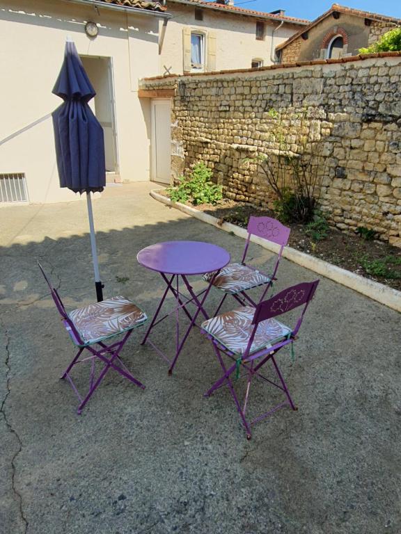 uma mesa roxa, duas cadeiras e um guarda-chuva em Maison d'hôtes du Faubourg Charrault Saint Maixent L'Ecole em Saint-Martin-de-Saint-Maixent