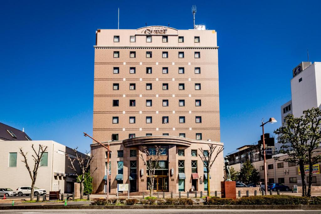 Un grand bâtiment blanc avec un panneau en haut dans l'établissement Hotel Quest Shimizu, à Shizuoka