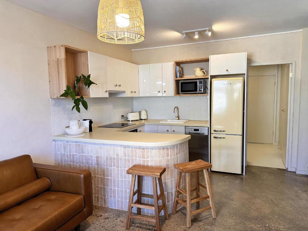 コフスハーバーにあるChic Beachside 2 Bedroom Apartment in Beautiful Coffs Harbourのキッチン(冷蔵庫、バースツール2つ付)