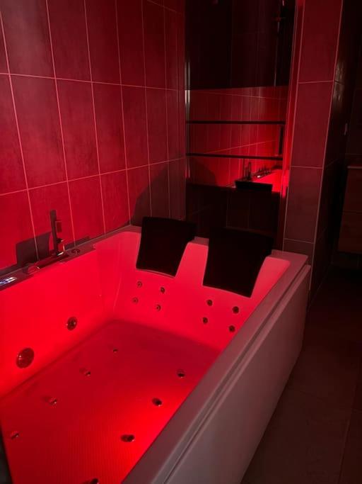 a red bath tub in a bathroom with red lighting at Mozart Cosy Love room in Chasse-sur-Rhône