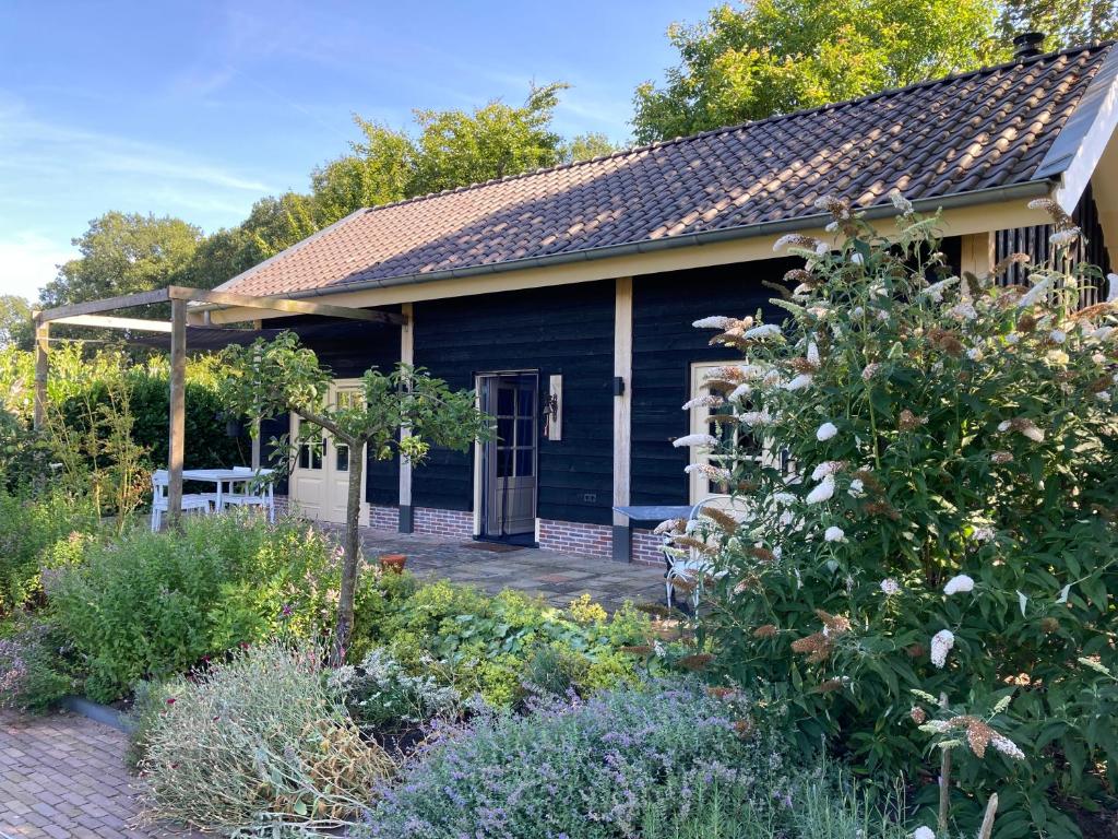 une maison bleue avec un jardin en face dans l'établissement Logeren bij De Soerensesteeg, à Uddel