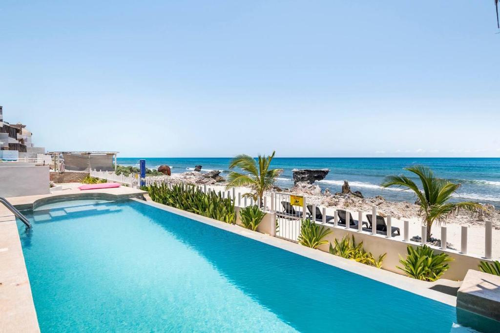 uma piscina com a praia ao fundo em Villas Najo' Isla Mujeres. em Ilha das Mulheres