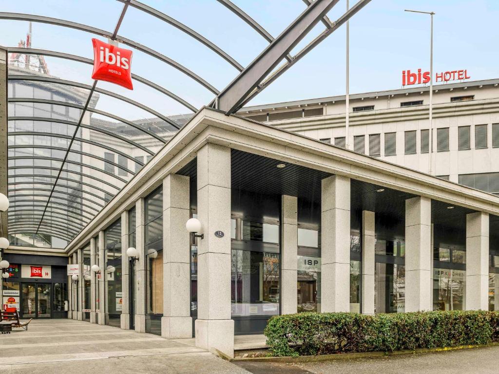 un grand bâtiment avec un arrêt de bus en face de celui-ci dans l'établissement ibis Luzern Kriens, à Lucerne