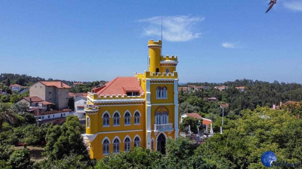 un bâtiment jaune avec une tour en haut dans l'établissement Vila Aurora, à Luso