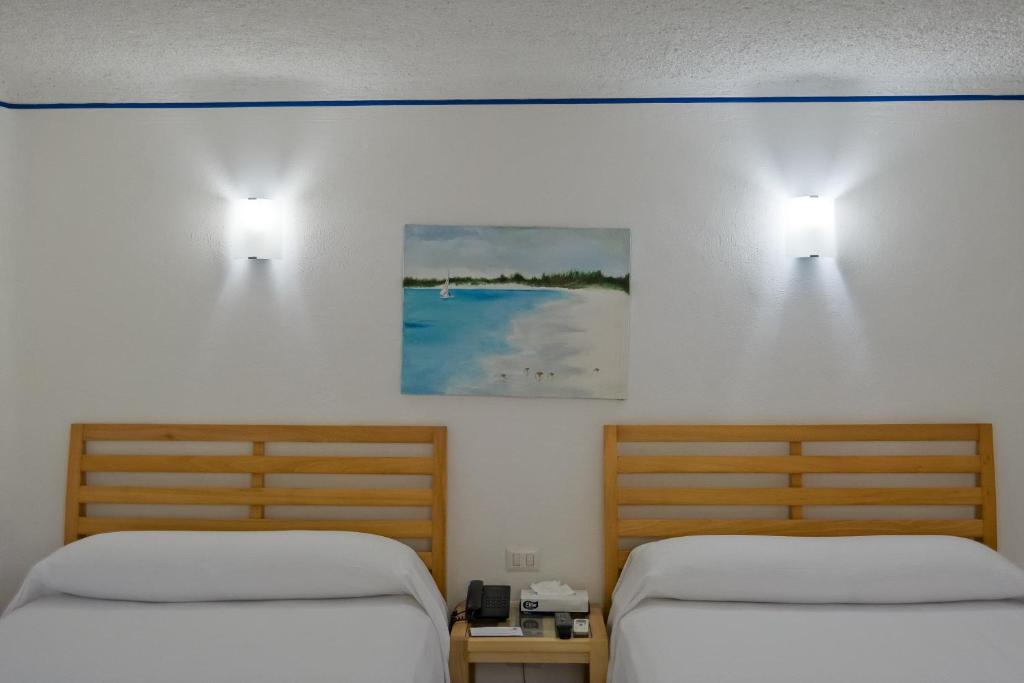 2 Betten in einem Zimmer mit 2 Lampen an der Wand in der Unterkunft Sotavento Hotel & Yacht Club in Cancún