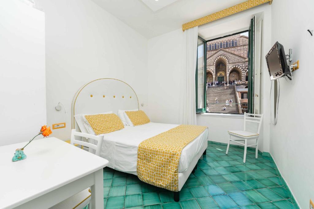 um pequeno quarto com uma cama e uma janela em Albergo S. Andrea em Amalfi