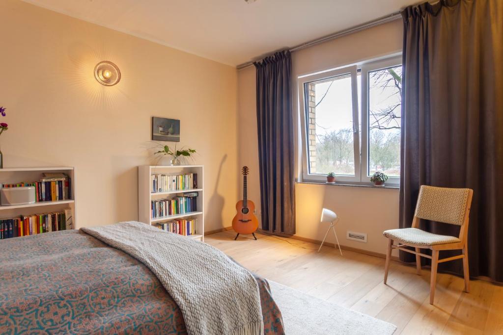 - une chambre avec un lit, une étagère et une guitare dans l'établissement Stilvolles Ambiente im grünen Hamburg!, à Hambourg