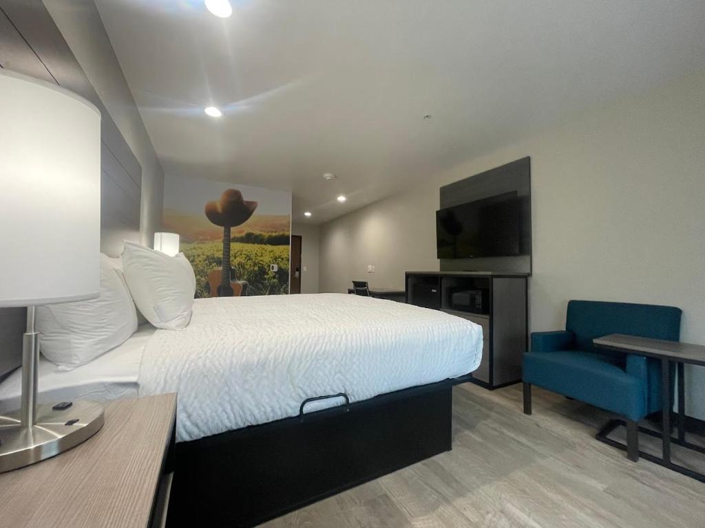 una camera d'albergo con letto e sedia blu di Clarion Pointe a Fort Worth