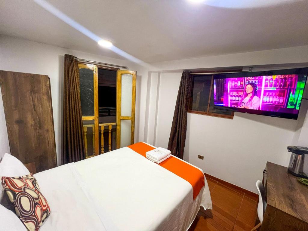 1 dormitorio con 1 cama y TV en la pared en Golden Paris Hotel "Mes de Aniversario", en Ayacucho