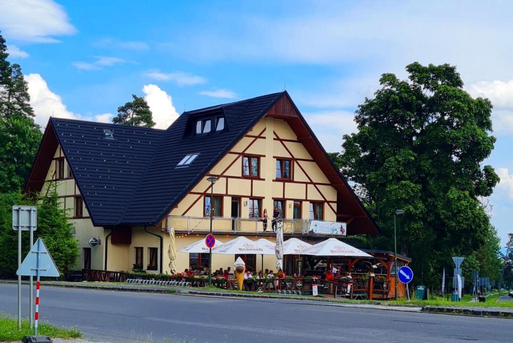 um edifício com um telhado preto com um restaurante em frente em Hotel Tulipan em Tatranská Lomnica