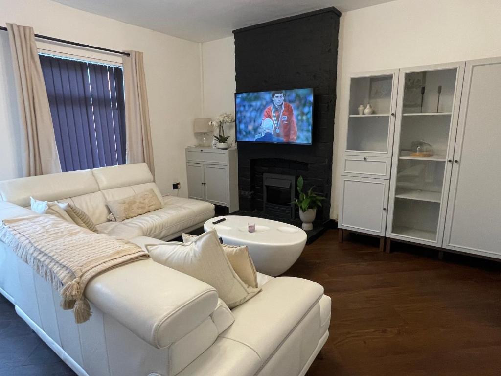 a living room with a white couch and a tv at Slick Space for a Standish Stay in Standish