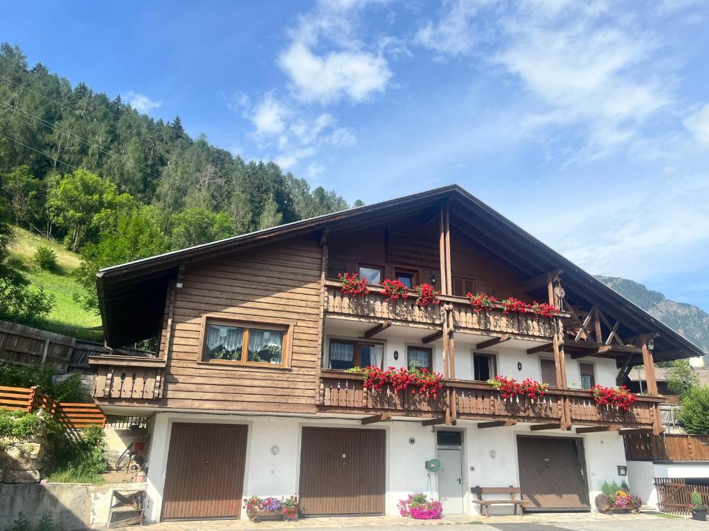 Casa in legno con balcone con fiori rossi di Stroblhof a Vipiteno