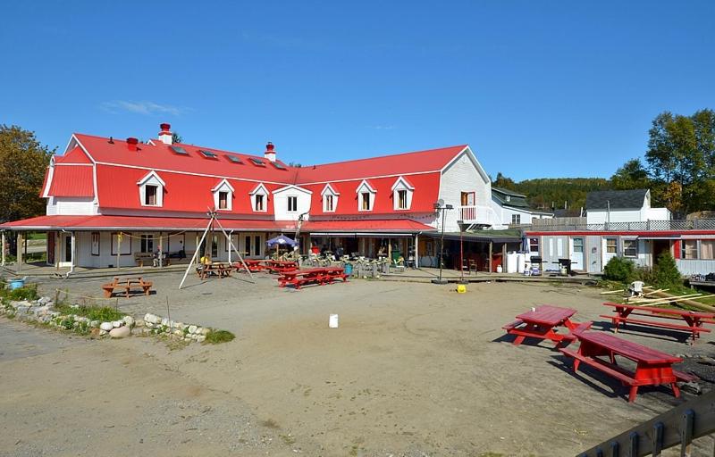 a large red building with picnic tables in front of it at Auberge jeunesse de Tadoussac in Tadoussac