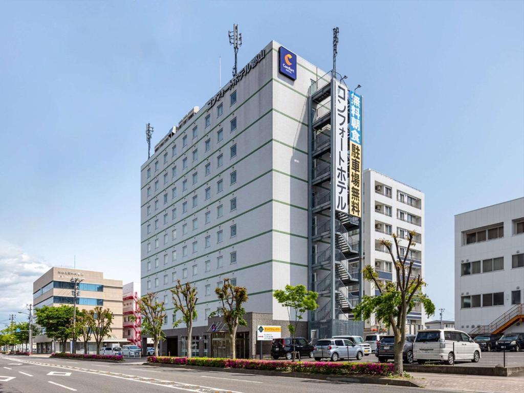 een wit gebouw met een bord aan de zijkant bij Comfort Hotel Koriyama in Koriyama