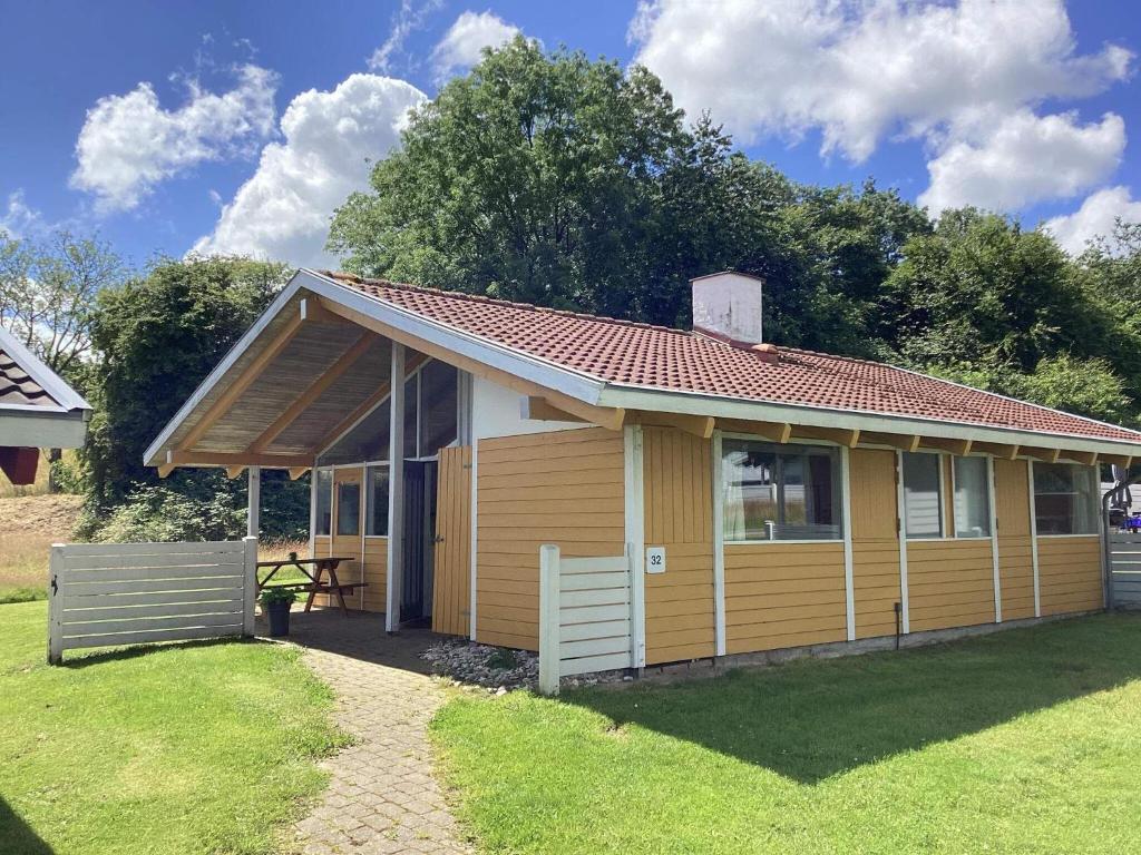 a small yellow house with a table in a yard at Holiday home Aabenraa LXXIX in Aabenraa