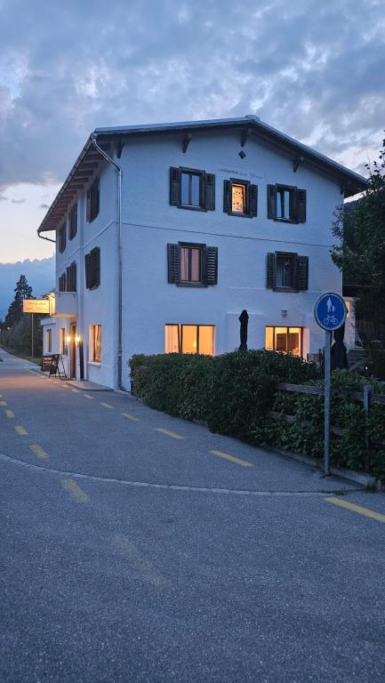 un bâtiment blanc avec des fenêtres sur le côté d'une rue dans l'établissement Landgasthof zum Glenner, à Ilanz