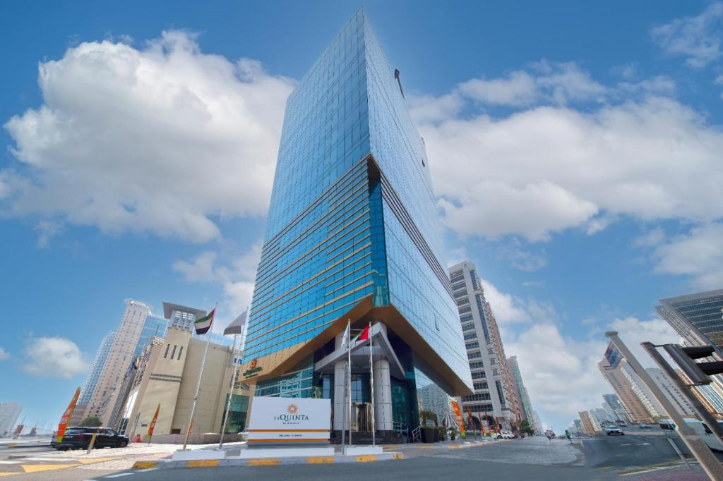 un edificio alto de cristal en medio de una ciudad en La Quinta by Wyndham Abu Dhabi Al Wahda, en Abu Dabi