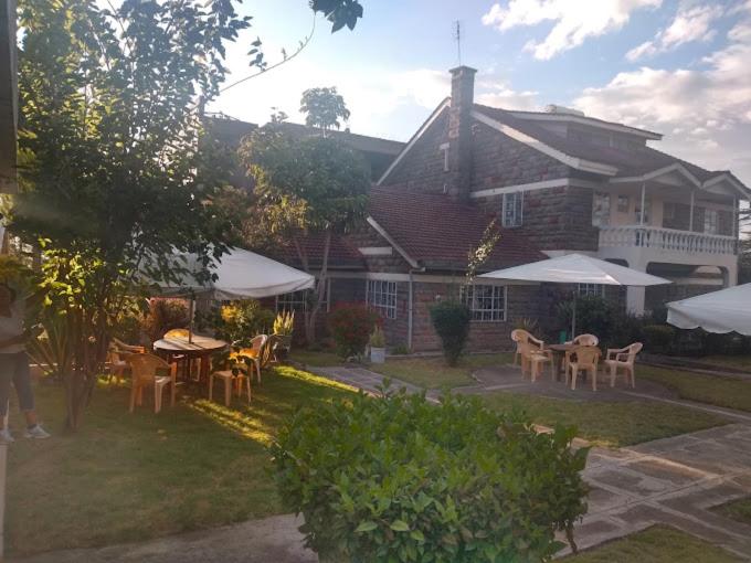 a yard with tables and chairs and a house at Taphe Resort Naivasha in Naivasha