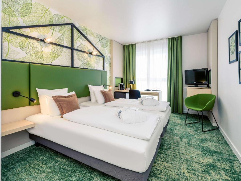 a hotel room with two beds and a tv at Mercure Hotel Hannover Mitte in Hannover