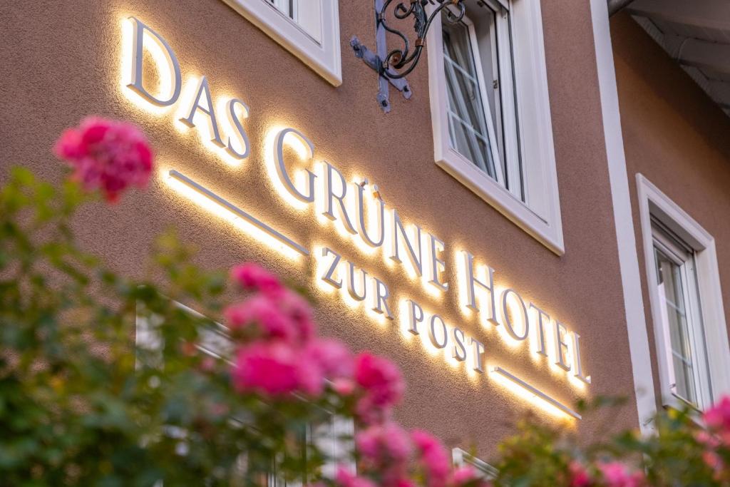 un cartello sul lato di un edificio con fiori rosa di Das Grüne Hotel zur Post - 100 % BIO a Salisburgo