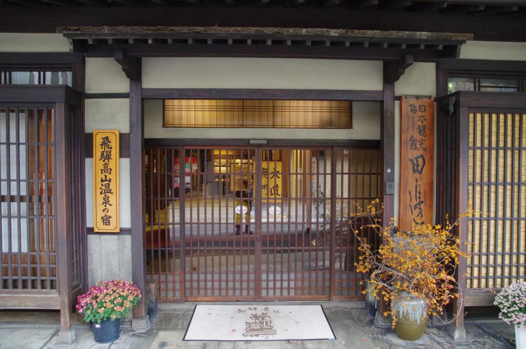 un ingresso a un edificio con cancello e fiori di Ryokan Tanabe a Takayama