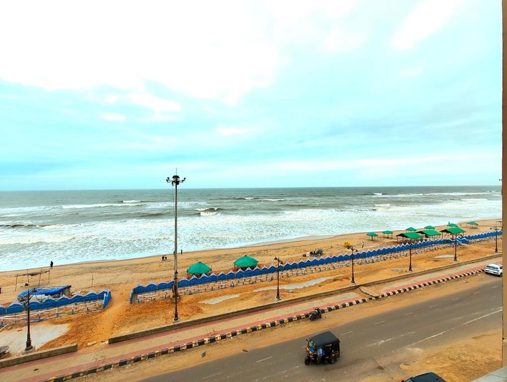 uma estrada junto a uma praia com guarda-sóis em SEA VIEW HOTEL DREAMLAND PURI -হোটেল ড্রিমল্যান্ড পুরী Rooms-sea view fully-air-conditioned-hotel with-lift-Restaurant-and-parking-facility - New marine Drive Road - Book Now em Puri