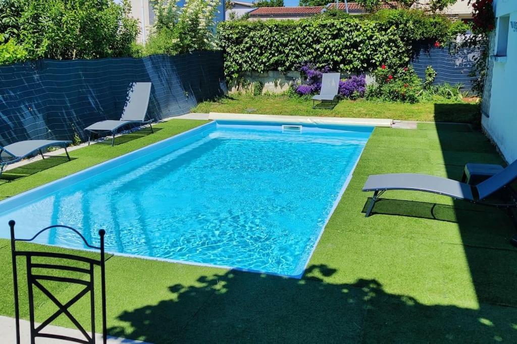 a swimming pool with two chairs and a table at Le Dragon - Appartement centre, Piscine partagée, Wifi, Jardin, Gare à 500m in Niort