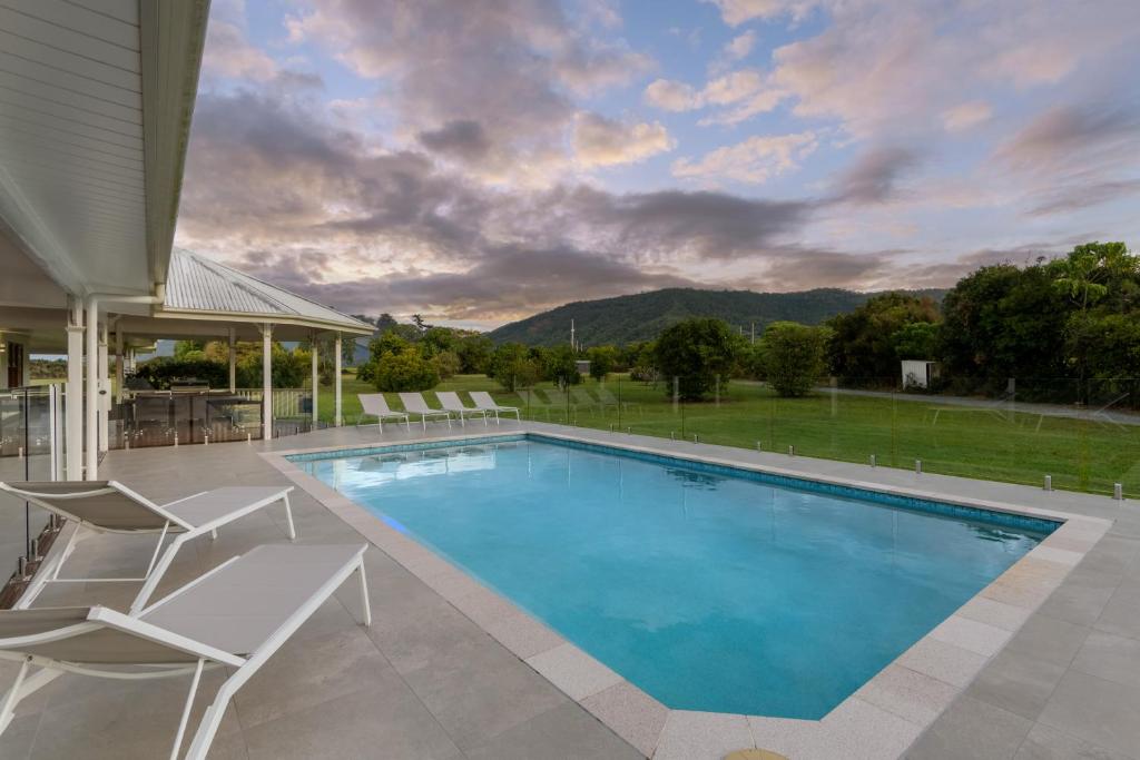 una piscina con sedie e una casa di The Hampton Lodge a Port Douglas