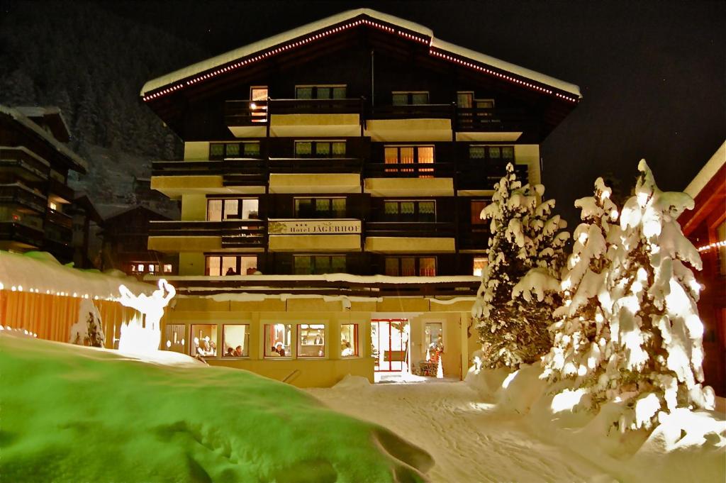 ein großes Gebäude mit schneebedeckten Bäumen davor in der Unterkunft Hotel Garni Jägerhof in Saas-Fee