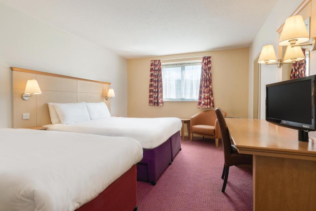 Cette chambre comprend deux lits, un bureau et une télévision. dans l'établissement Days Inn Winchester, à Winchester