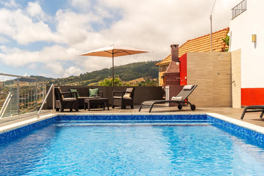 - une piscine avec des chaises et un parasol dans un bâtiment dans l'établissement Roraima House - Private Pool & Garden, à Calheta