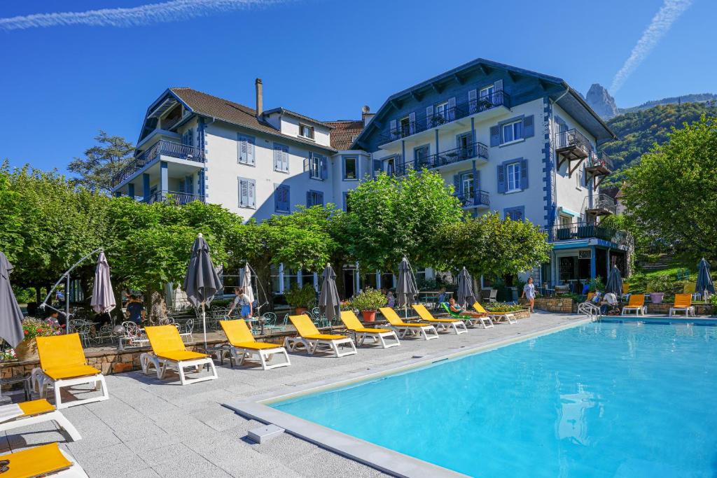 a hotel with a swimming pool and chairs and a building at Hotel du Lac in Talloires