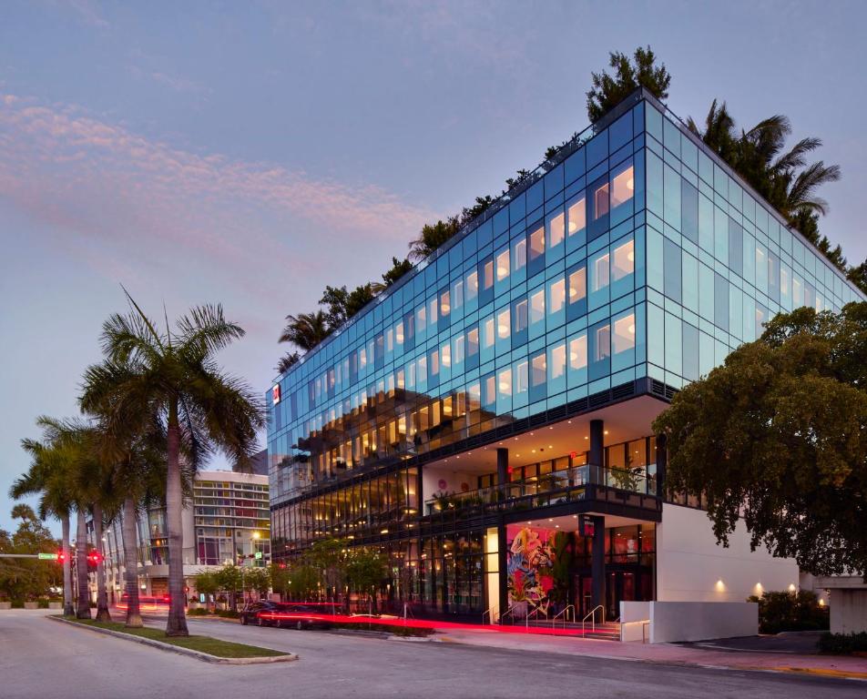 een hoog glazen gebouw met een palmboom ervoor bij citizenM Miami South Beach in Miami Beach