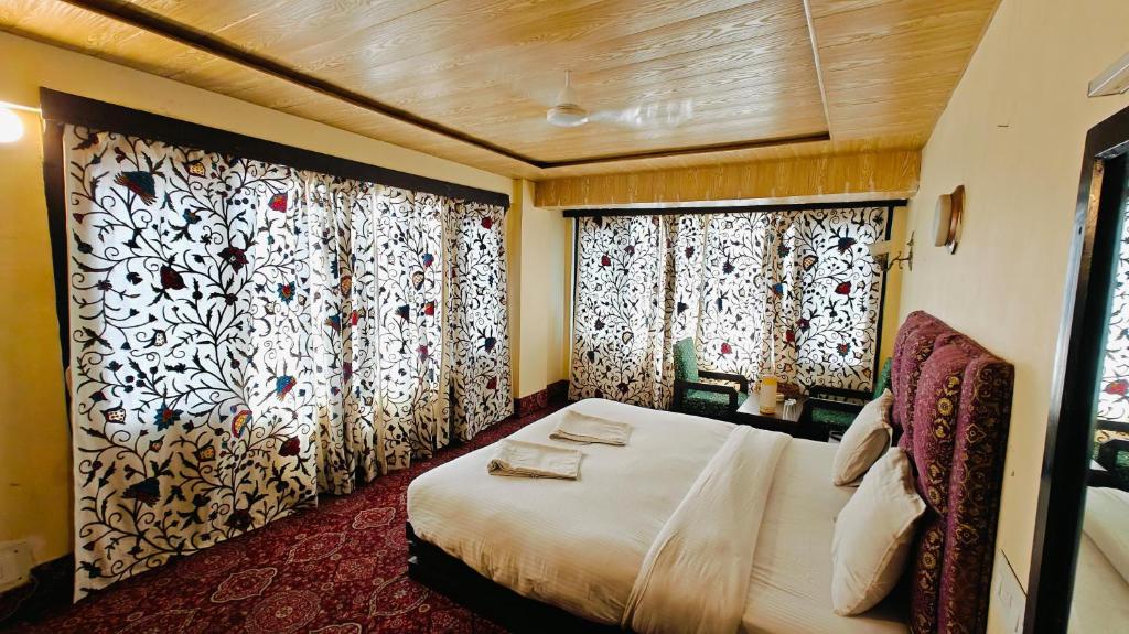 um quarto com uma cama e duas janelas com cortinas em Hotel kabir em Srinagar