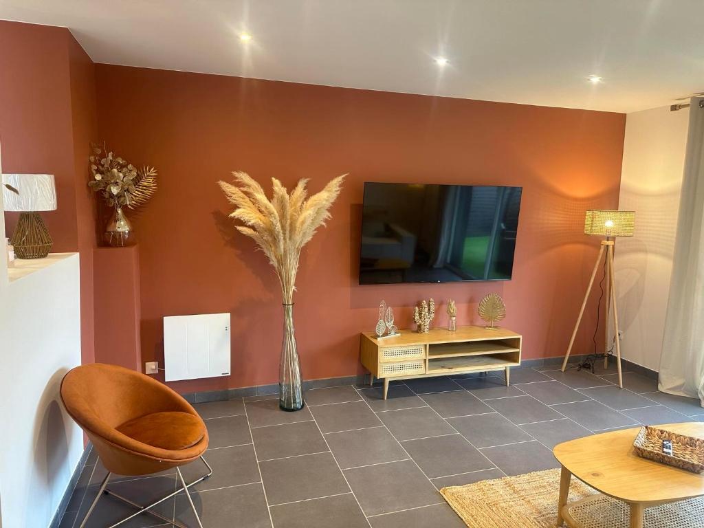 un salon avec une télévision et un vase de fleurs dans l'établissement Logement cosy proche plage wissant, à Marquise