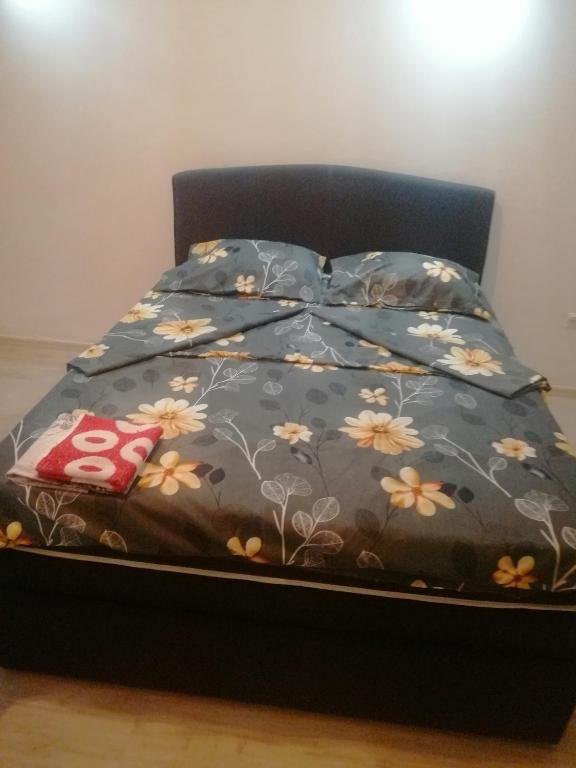 uma cama com um edredão preto com flores em Sindi Apartman em Bačka Palanka