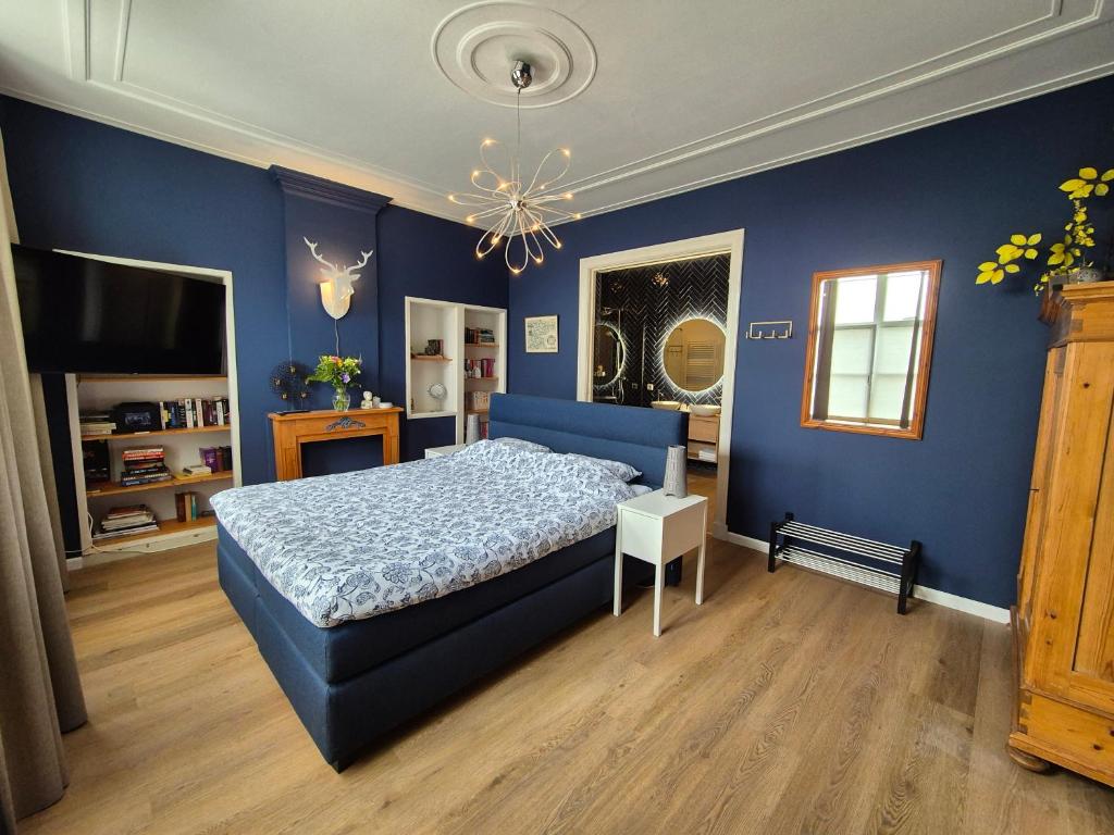 ein blaues Schlafzimmer mit einem Bett und einem Kronleuchter in der Unterkunft B&B van Zon aan Zee in Vlissingen