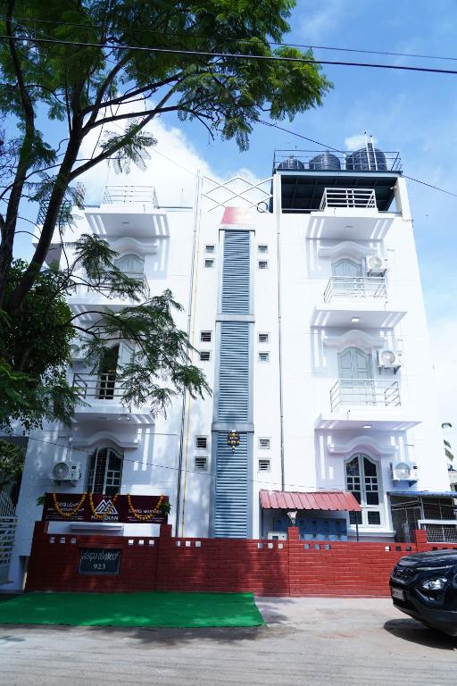 een wit gebouw met een rood hek ervoor bij Meridian Rooms and Service Apartment in Mysore