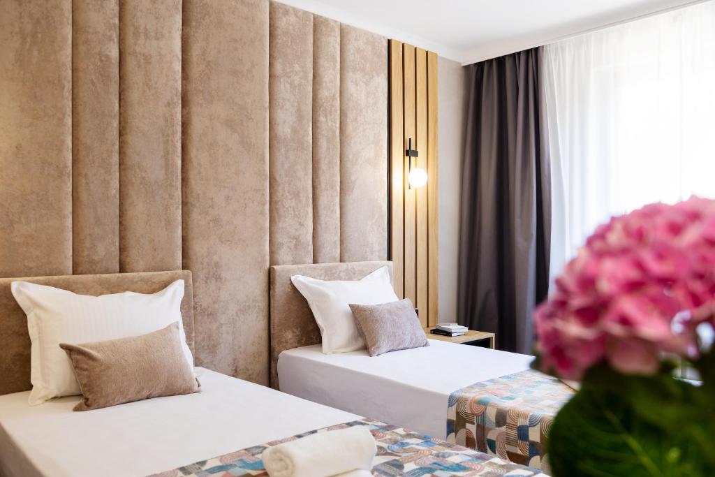 Dos camas en una habitación de hotel con flores rosas en AMAR Design Hotel by HMG, en Sofía