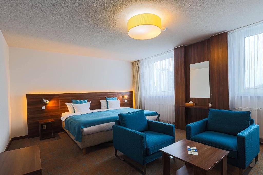 een hotelkamer met een bed en twee blauwe stoelen bij Hotel Metropol in Spišská Nová Ves