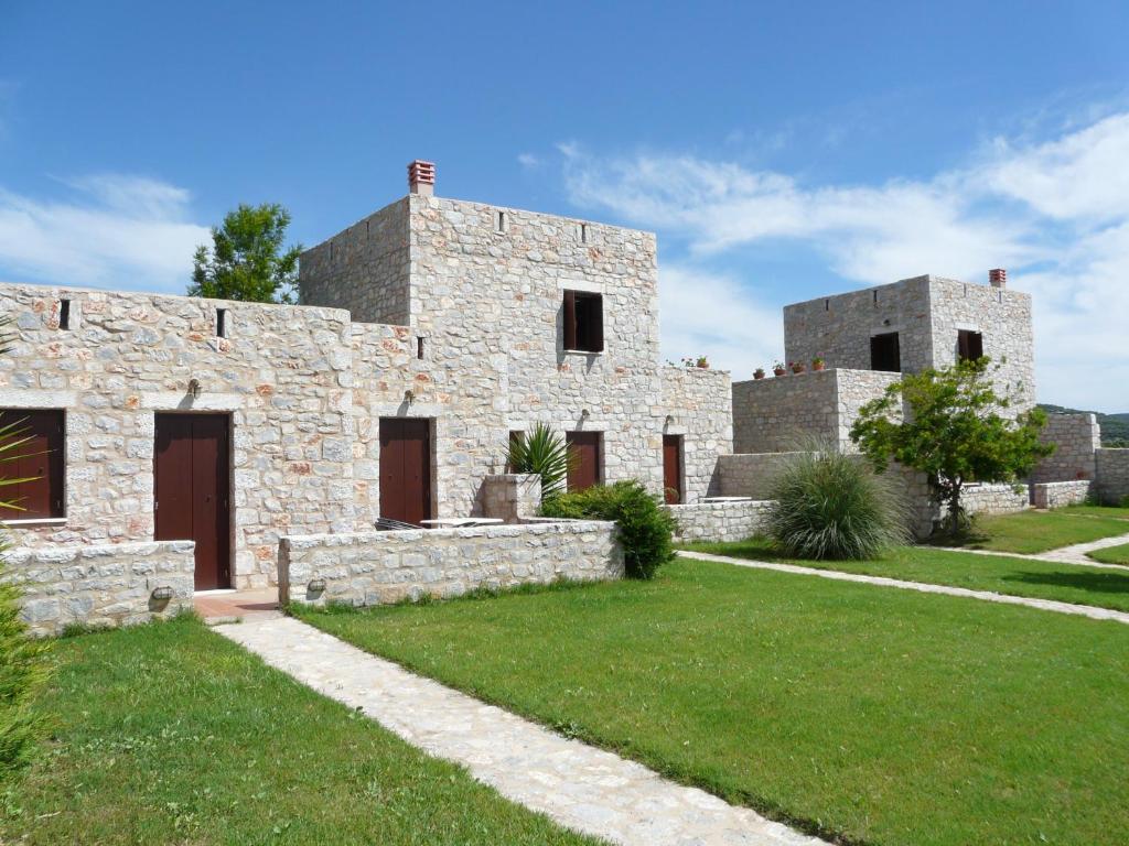 una casa de piedra con un césped verde delante de ella en Ktima Petalea, en Gythio