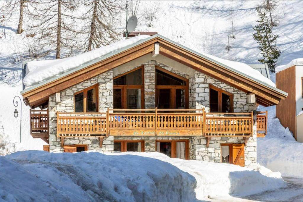 een blokhut met een terras in de sneeuw bij Appartement chaleureux au Chalet Barme de l'Ours 2 in Val dʼIsère