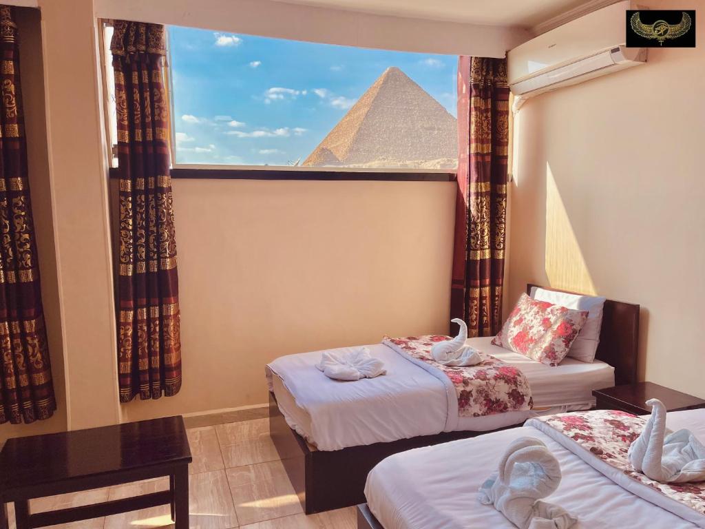 Habitación con 2 camas y una pirámide en la ventana en Comfort Sphinx&Pyramids Inn en El Cairo