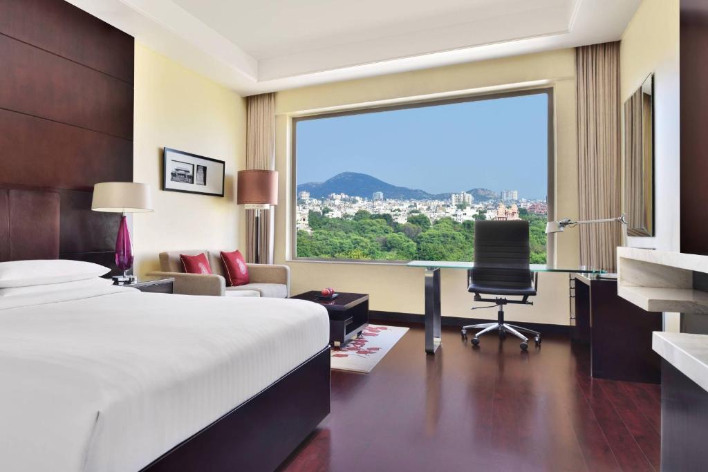 a hotel room with a bed and a desk and a window at Jaipur Marriott Hotel in Jaipur