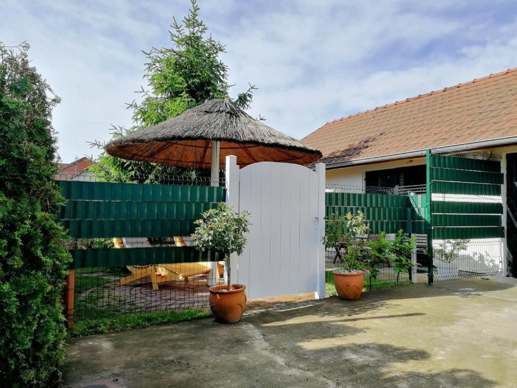 a fence with an umbrella and a table and bench at Apartman TESLA 29 in Veternik