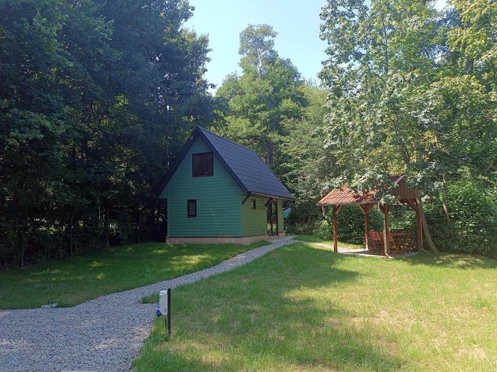 uma casa verde com um gazebo num quintal em Mókuska erdőszéli faházikó em Parád