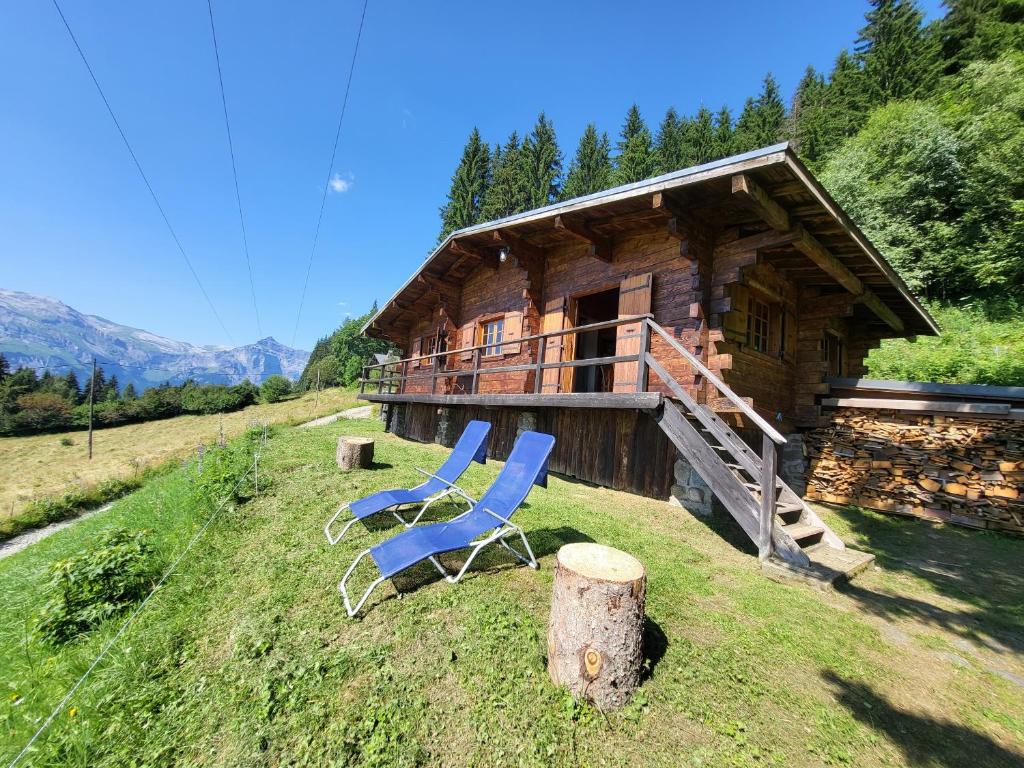 duas cadeiras azuis sentadas fora de uma cabana de madeira em Chalet d'alpage avec vue incroyable em Saint-Gervais-les-Bains