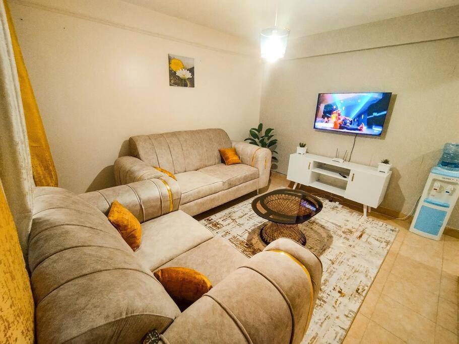 - un salon avec deux canapés et une télévision à écran plat dans l'établissement Cosy Homes Eldoret, à Eldoret