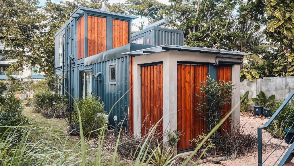 een klein huis met oranje deuren in een tuin bij OBOĒ Gardenstē in Pereybere